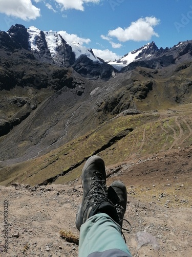 A pair of legs with hiking boots on and a mountain view