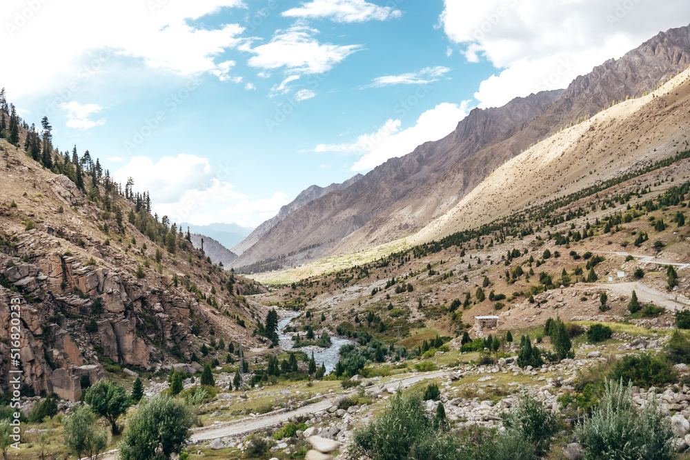 wide landscape of a river flowing through the mountains of Astore Valley in Pakistan on a sunny summer day