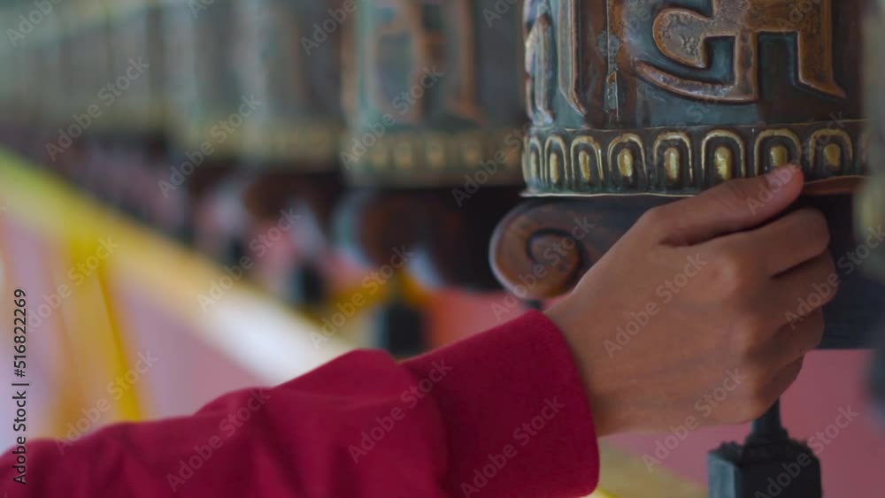 Close up shot of young girl hand spinning Buddhist Prayer wheels at monastery at Manali Mall Road, Himachal Pradesh, India. Religious prayer wheels in Himachal Pradesh Close up shot of young girl hand spinning Buddhist Prayer wheels at monastery at Manali Mall Road, Himachal Pradesh, India. Religious prayer wheels in Himachal Pradesh