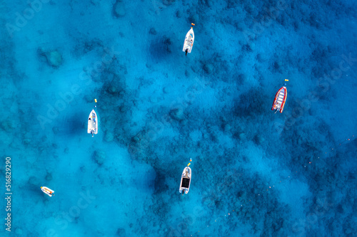 Aerial view of the boats in clear blue water at sunset in summer. Top view from drone of yachts, sandy beach in mediterranean sea. Travel in Oludeniz, Turkey. Tropical landscape with motorboats © den-belitsky