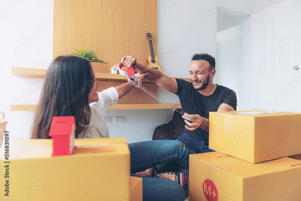Couple packing stuff among plenty of cardboard boxes Couple packing stuff among plenty of cardboard boxes