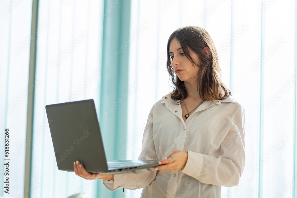 Business woman thinks while using her laptop in a co-working office Business woman thinks while using her laptop in a co-working office