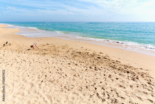 Girl alone doing a pirouette on the beach by the sea