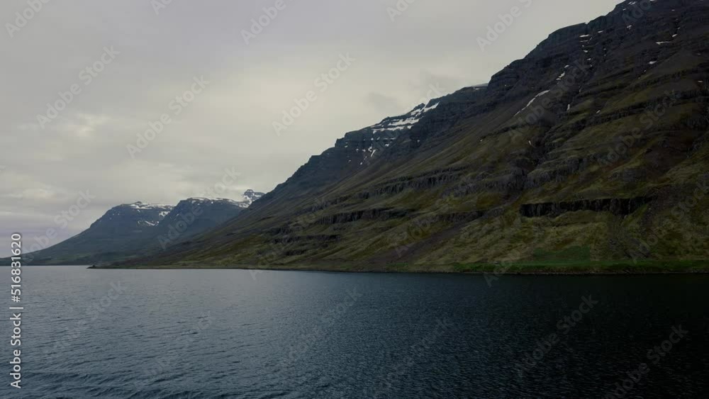 Shoreline with snow covered mountain range and calm body of water in Iceland Shoreline with snow covered mountain range and calm body of water in Iceland