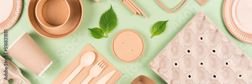 Flat lay banner background with eco tableware, paper utensils and wooden bamboo cutlery set over light green background. Sustainable food packaging concept
