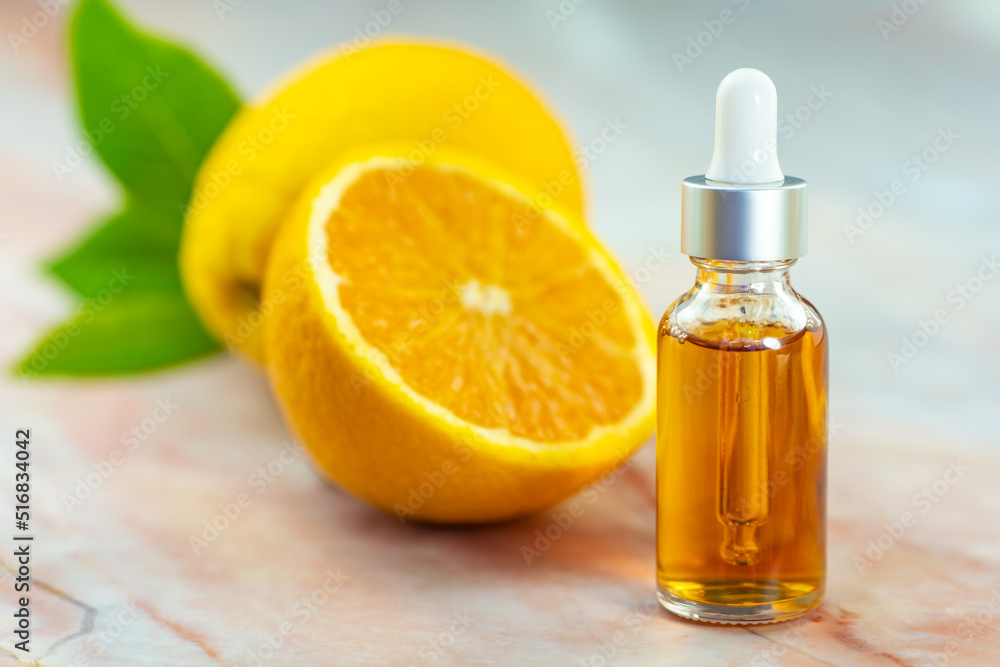 Serum in a cosmetic bottle next to an orange. Natural cosmetics and face care. Serum in a cosmetic bottle next to an orange. Natural cosmetics and face care.