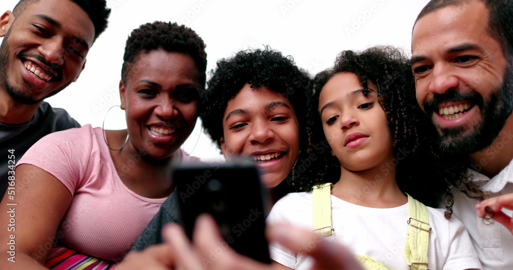 Obraz premium Diverse interracial family at home couch looking at cellphone