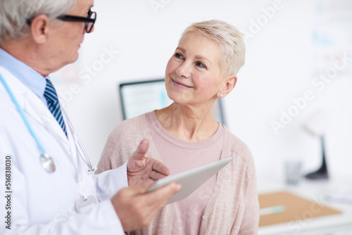 Smiling healthy senior female patient with short hair listening to doctor who giving treatment advice