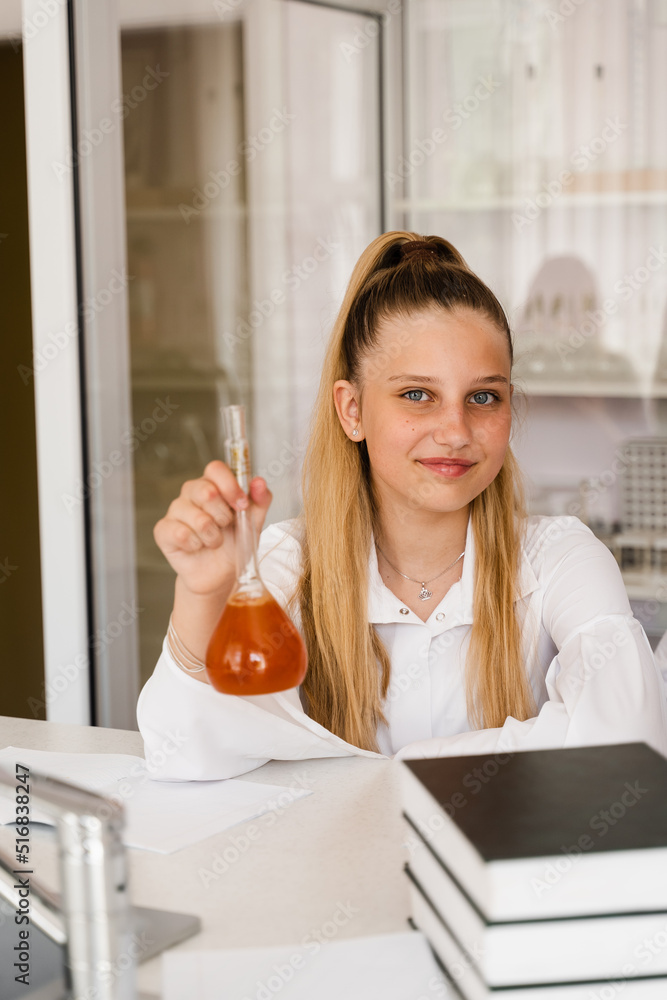 Chemistry lesson at school. Girl with flask is studying in chemistry classroom. Schoolgirl holding flask with chemical in the laboratory.