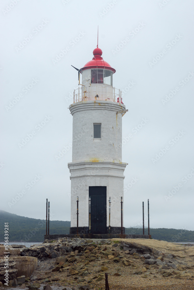 Vladivostok. Lighthouse Egersheld (1876) at the tip of the Shkota peninsula - Tokarevskaya cat in the evening in cloudy weather. Russia July 2022