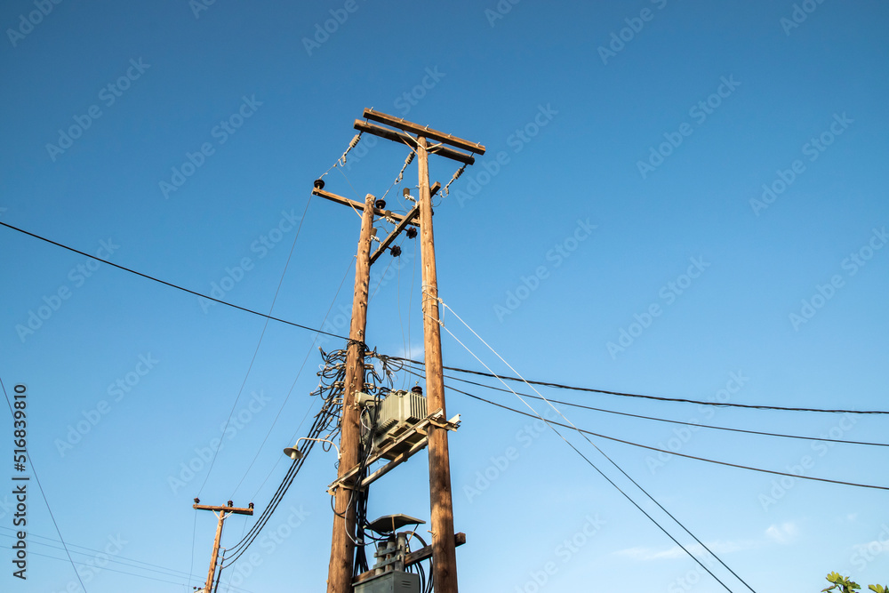 External transformer on wooden poles connected into electric energy on blue sky background