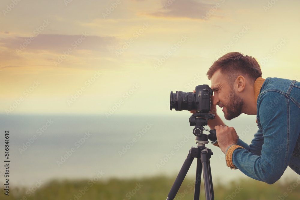 Photographer taking picture of beautiful landscape with professional camera outdoors. Space for text