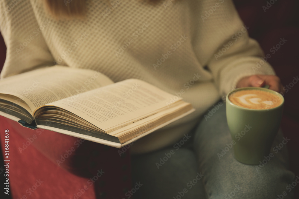 Woman with cup of coffee reading book indoors, closeup Woman with cup of coffee reading book indoors, closeup