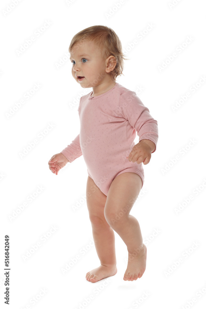 Cute baby girl in pink bodysuit learning to walk on white background Cute baby girl in pink bodysuit learning to walk on white background
