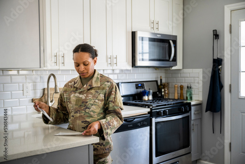 Fotografi U.S. Army female soldier opening her mail in her kitchen
