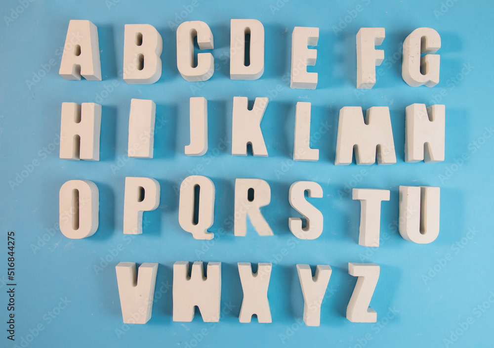 White concrete letters on a blue background. Letters of the alphabet. The concept is time to school, study White concrete letters on a blue background. Letters of the alphabet. The concept is time to school, study