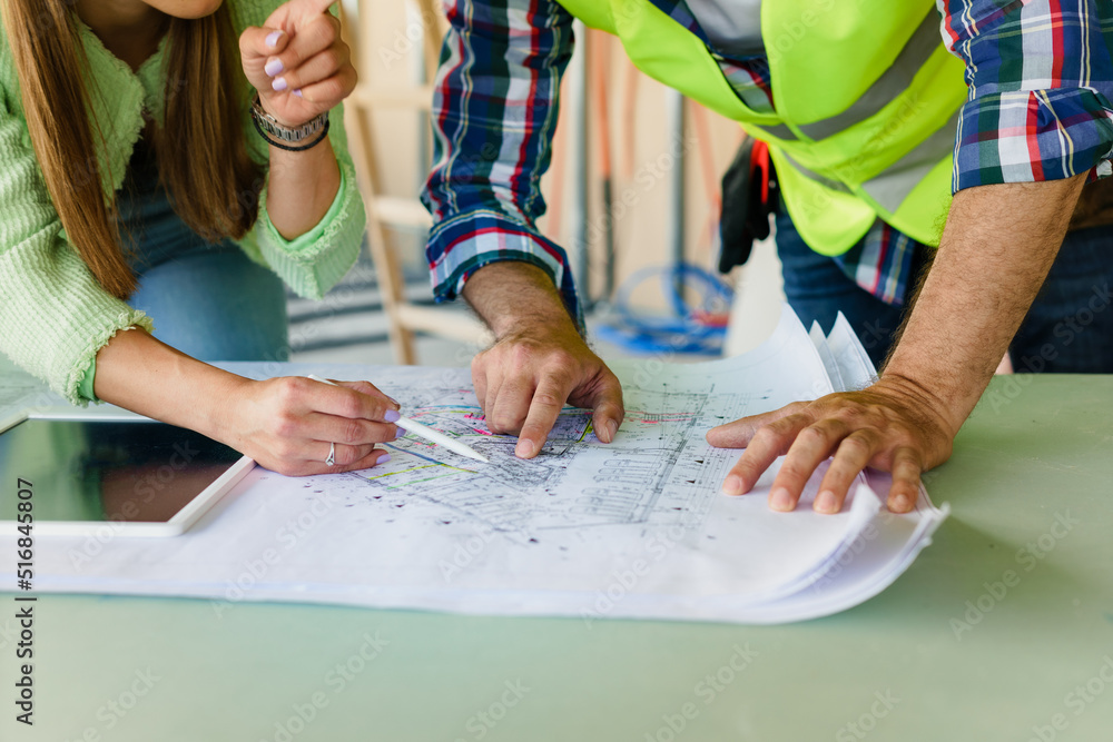 Woman architect explaining blueprint to supervisor at construction site. Engineer talking to contractor. Woman architect explaining blueprint to supervisor at construction site. Engineer talking to contractor.
