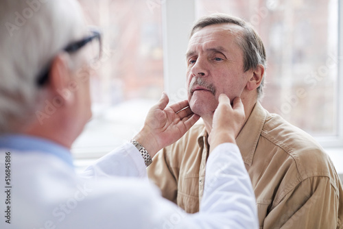 Bilde på lerret Over shoulder view of doctor checking lumps on neck of aged male patient with mu
