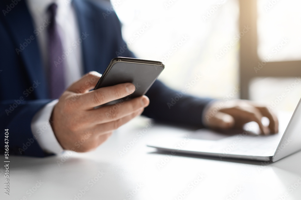 Unrecognizable Male Entrepreneur Using Smartphone And Working With Laptop In Office Unrecognizable Male Entrepreneur Using Smartphone And Working With Laptop In Office