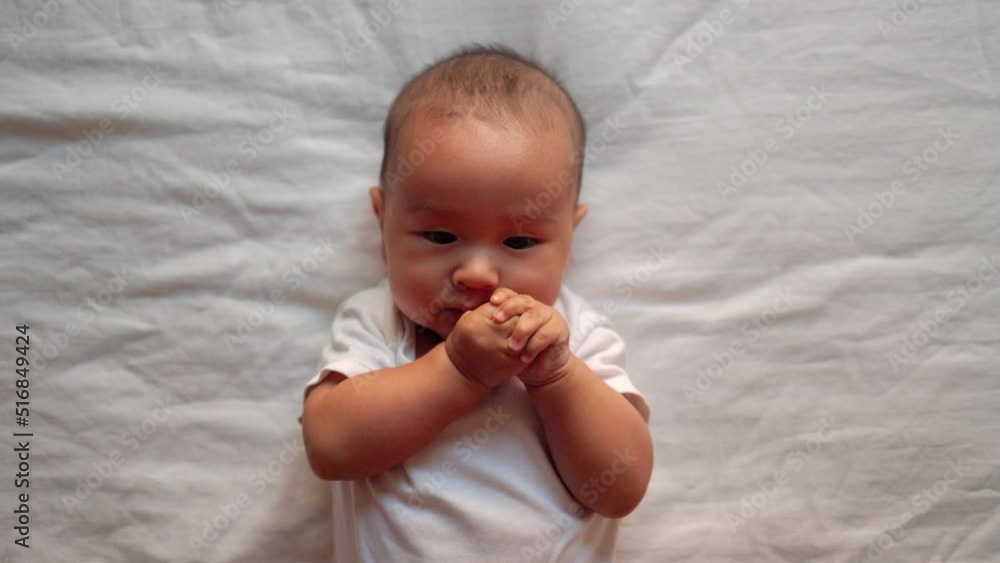 Cute asian baby moves his hands and put them into mouth Cute asian baby moves his hands and put them into mouth