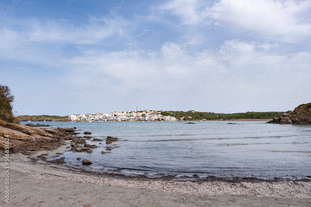 Mediterranean fishing village with white houses in a turquoise water bay, with sport boats on the water on a sunny day