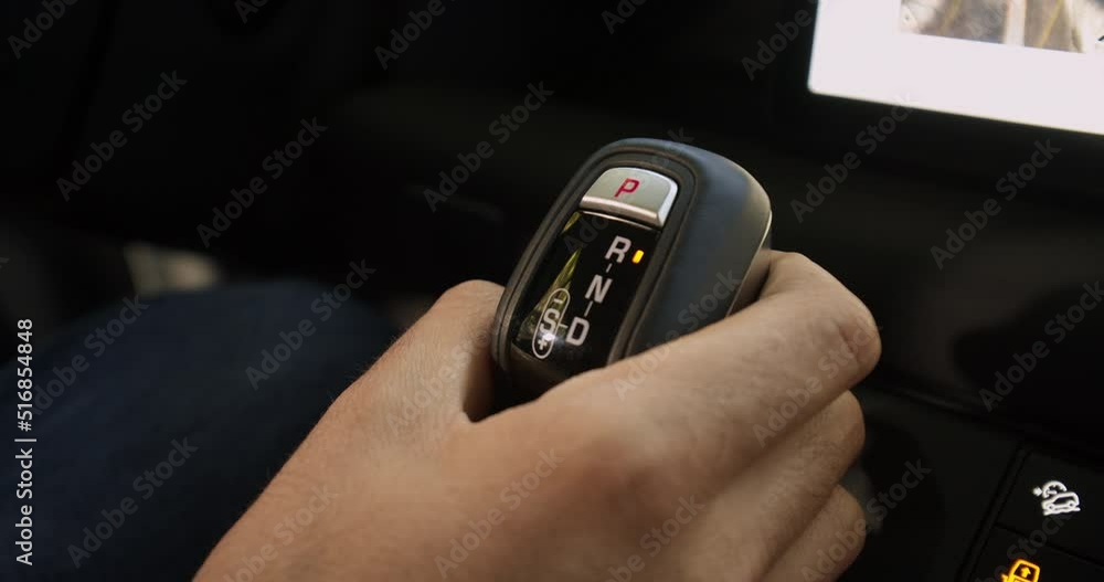 A Caucasian Man hand changes automatic gear selector from Drive to Reverse in a luxury off road suv in a sunny day under the forest A Caucasian Man hand changes automatic gear selector from Drive to Reverse in a luxury off road suv in a sunny day under the forest