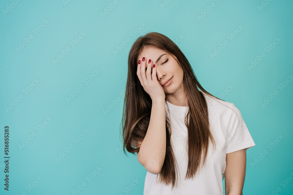 A tired, sleepy woman holds her head by hand, with a sad expression on her face, closes her eyes, can't wake up in the morning and go to work on a difficult, hard Monday. isolated turquoise backdrop A tired, sleepy woman holds her head by hand, with a sad expression on her face, closes her eyes, can't wake up in the morning and go to work on a difficult, hard Monday. isolated turquoise backdrop