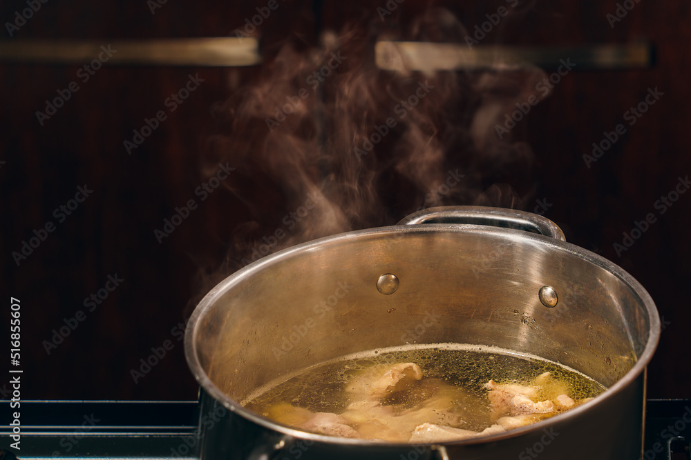 Close-up of broth in a steel saucepan on the stove, pieces of white chicken meat are boiled in a saucepan, hot meat broth for soup. Top view, copy space Close-up of broth in a steel saucepan on the stove, pieces of white chicken meat are boiled in a saucepan, hot meat broth for soup. Top view, copy space