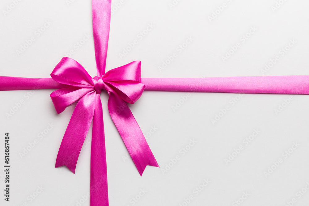 Top view of purple ribbon rolled and pink bow isolated on colored background. Flat lay with copy space Top view of purple ribbon rolled and pink bow isolated on colored background. Flat lay with copy space