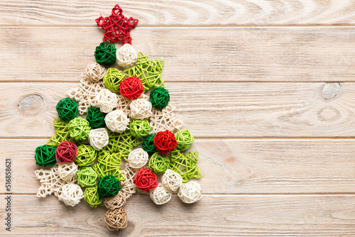 Christmas tree made from colored handmade ball decoration on colored background, view from above. New Year minimal concept with copy space