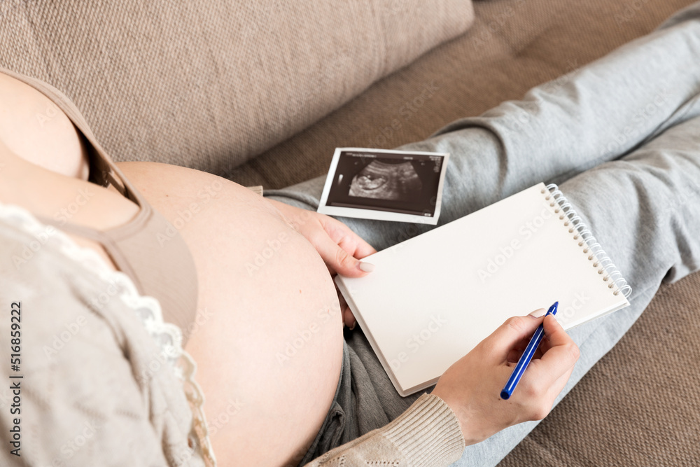 top-view-caring-future-mother-writing-diary-with-ultrasound-pregnant