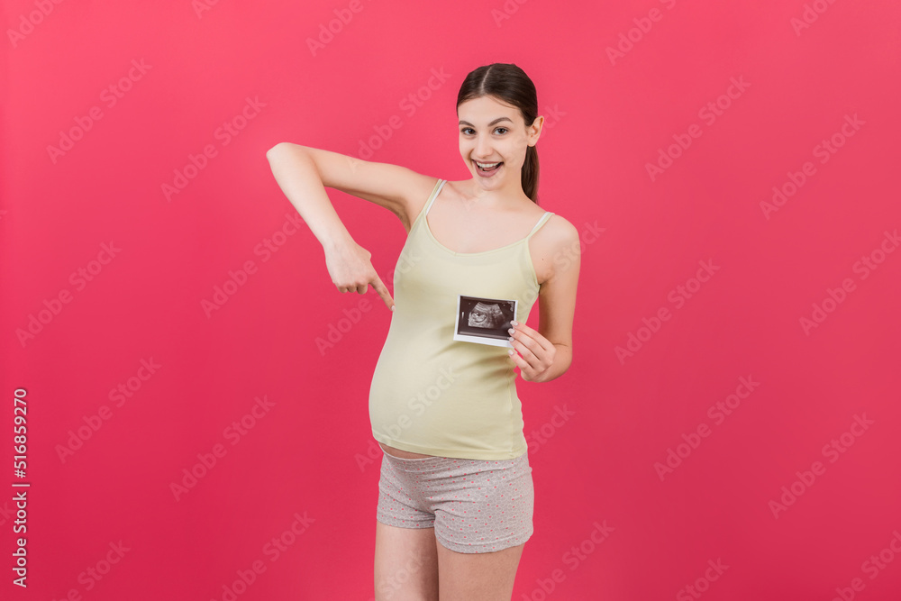 Cute Pregnant Lady Posing With Baby Sonography Photo Near Colored background. Concept of pregnancy, gynecology, medical test, maternal health