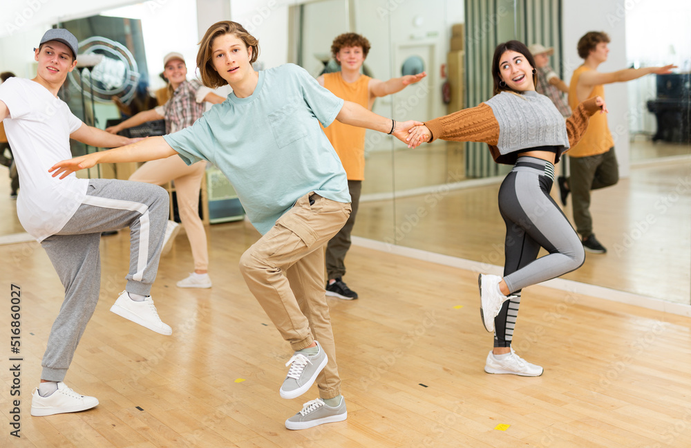 Teenager girls and boys performing jive dance in ballroom.