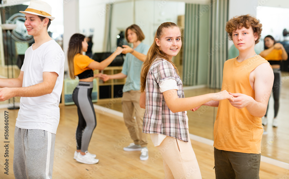 Interested modern teens learning to dance waltz in pairs in choreographic studio .