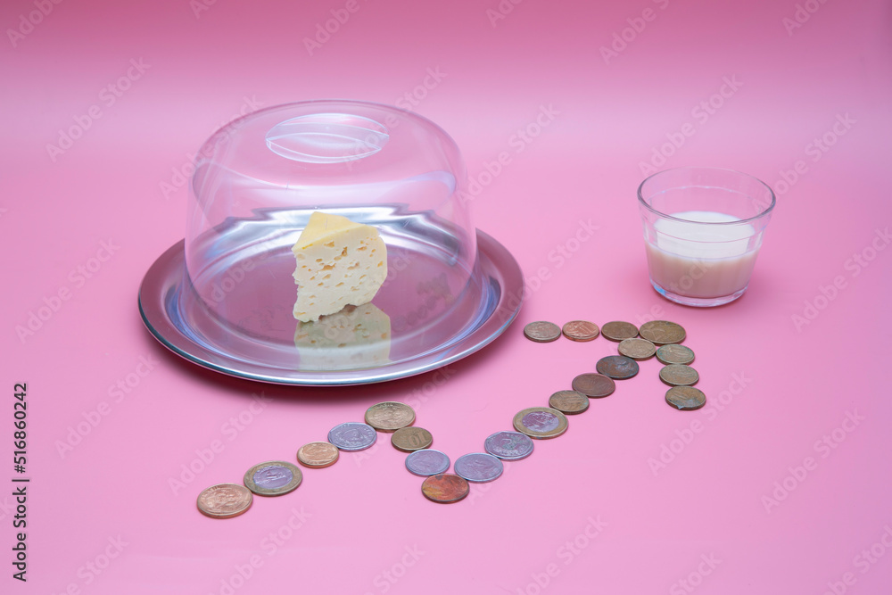 small glass of milk with slice of cheese with graph of price increase written with coins small glass of milk with slice of cheese with graph of price increase written with coins