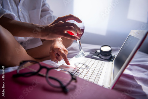 relaxed businesswoman working on her computer with her wine