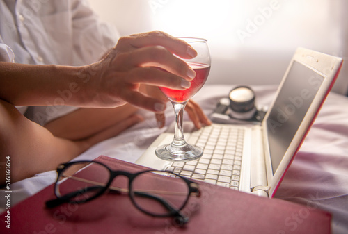 relaxed businesswoman working on her computer with her wine