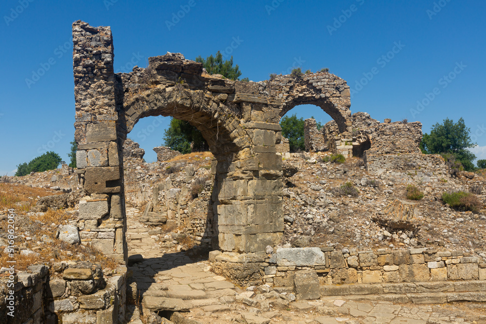 View of remains of buildings and eastern city gate over ancient road of Aspendos antique town, Turkey