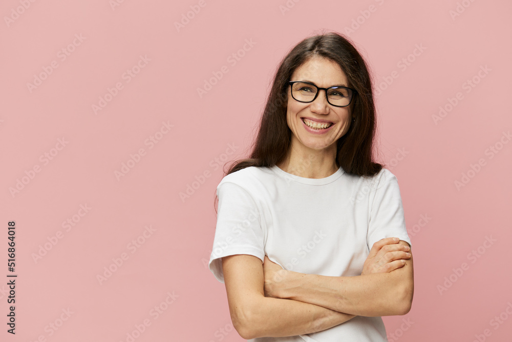 Obraz premium portrait of a cute, attractive brunette in a white tank top on a pink background, with a pleasant smile, standing in glasses for vision