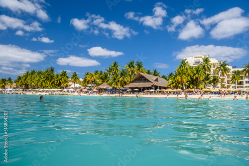 People swimming near white sand beach with umbrellas, bungalow bar and cocos palms, turquoise caribbean sea, Isla Mujeres island, Caribbean Sea, Cancun, Yucatan, Mexico © Eagle2308