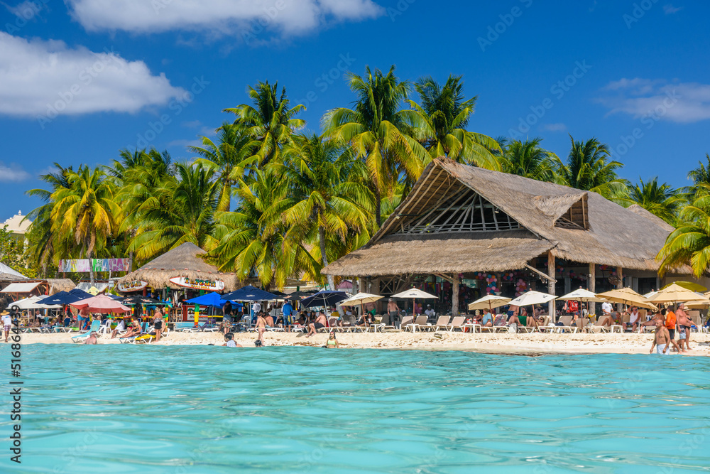 People sunbathing on the white sand beach with umbrellas, bungalow bar and cocos palms, turquoise caribbean sea, Isla Mujeres island, Caribbean Sea, Cancun, Yucatan, Mexico