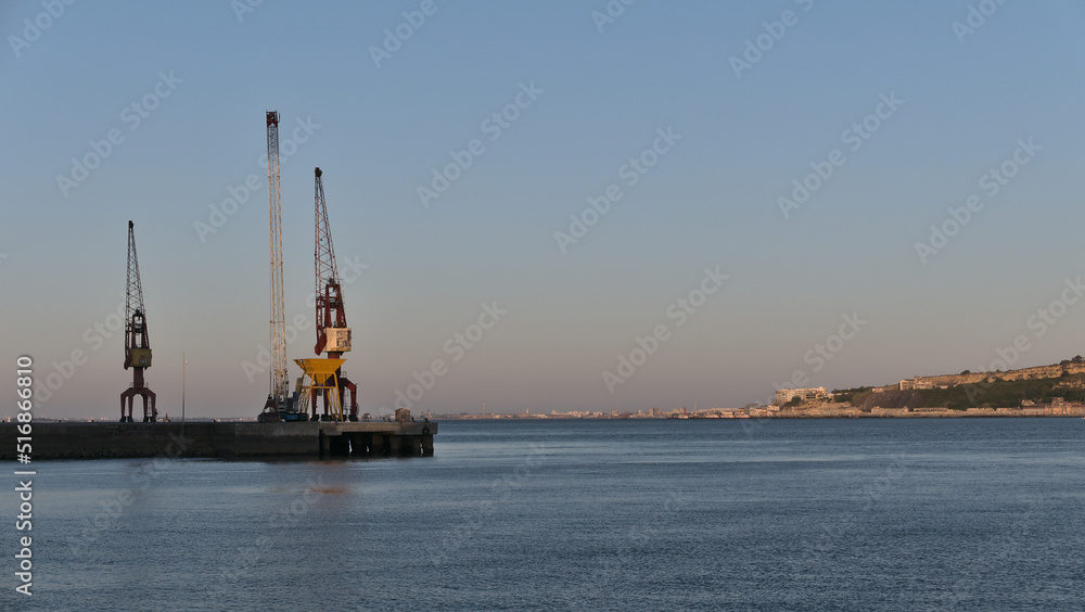 Cranes in Industrial harbor on the Tagus river in summer evening, Lisbon, Portugal