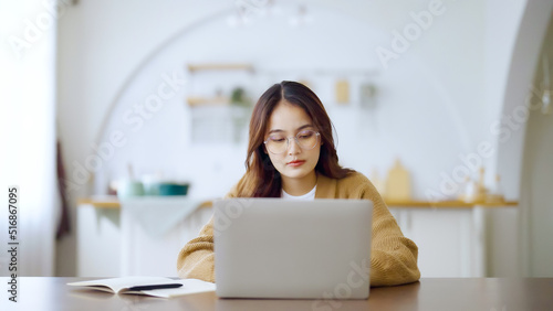 Free Download Smiling asian young woman working on laptop at home office. Young asian student using computer remote studying, virtual training, e-learning, watching online education webinar at house - GFXLoad