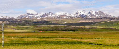 Fields in front of mountains with snow under cloudy day in Iceland 