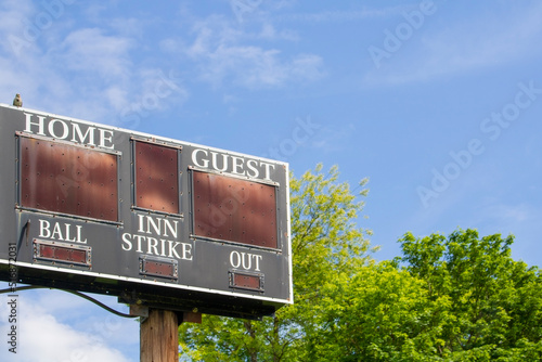 sports area score board sign home vs visitors and blue sky with trees