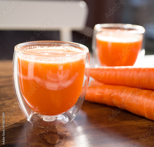 Принти на полотні Organic carrot juice in glass on dark wooden background