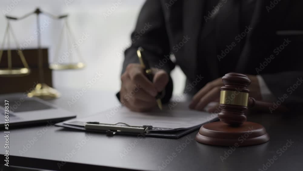Attorney's office Hammer placed in front and statue of scales placed next to lawyers signing contracts and stamps on documents 4k video Attorney's office Hammer placed in front and statue of scales placed next to lawyers signing contracts and stamps on documents 4k video