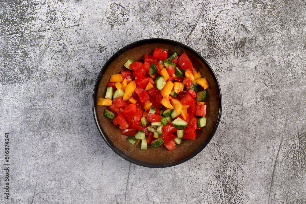 Summer homemade tomato and cucumbers salad in a bowl on a dark background. Top view, flat lay Summer homemade tomato and cucumbers salad in a bowl on a dark background. Top view, flat lay
