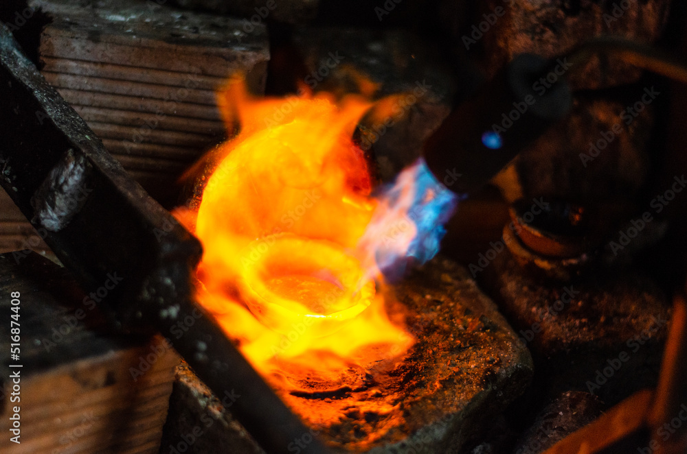 Fototapeta premium Close up of Jeweler crafting golden bracelet with flame torch