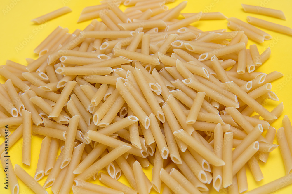 scattered pasta feathers on light yellow background scattered pasta feathers on light yellow background